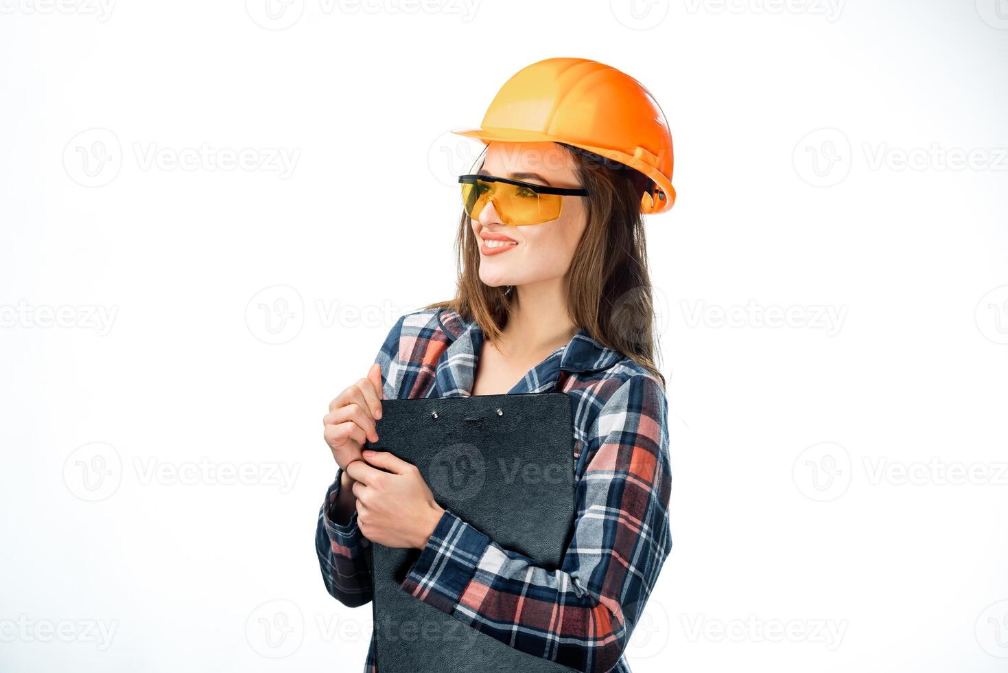 lindo sério fêmea arquiteto com escrevendo o negócio planos isolado em branco. atraente trabalhador dentro capacete e óculos detém Preto pasta foto