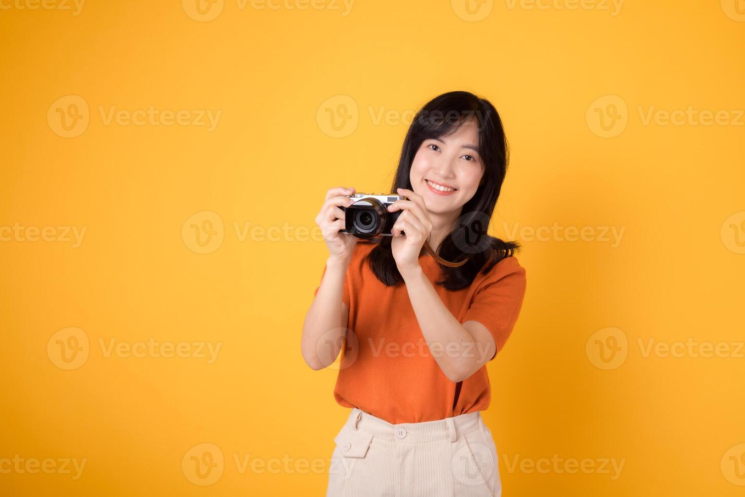 jovem senhora segurando uma Câmera isolado em amarelo fundo, transmitindo a excitação do uma viagem aventura. foto