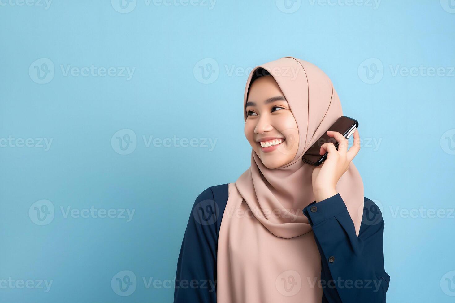 ai gerado fofa jovem ásia menina dentro hijab segurando uma Smartphone dentro frente do uma vibrante azul fundo foto