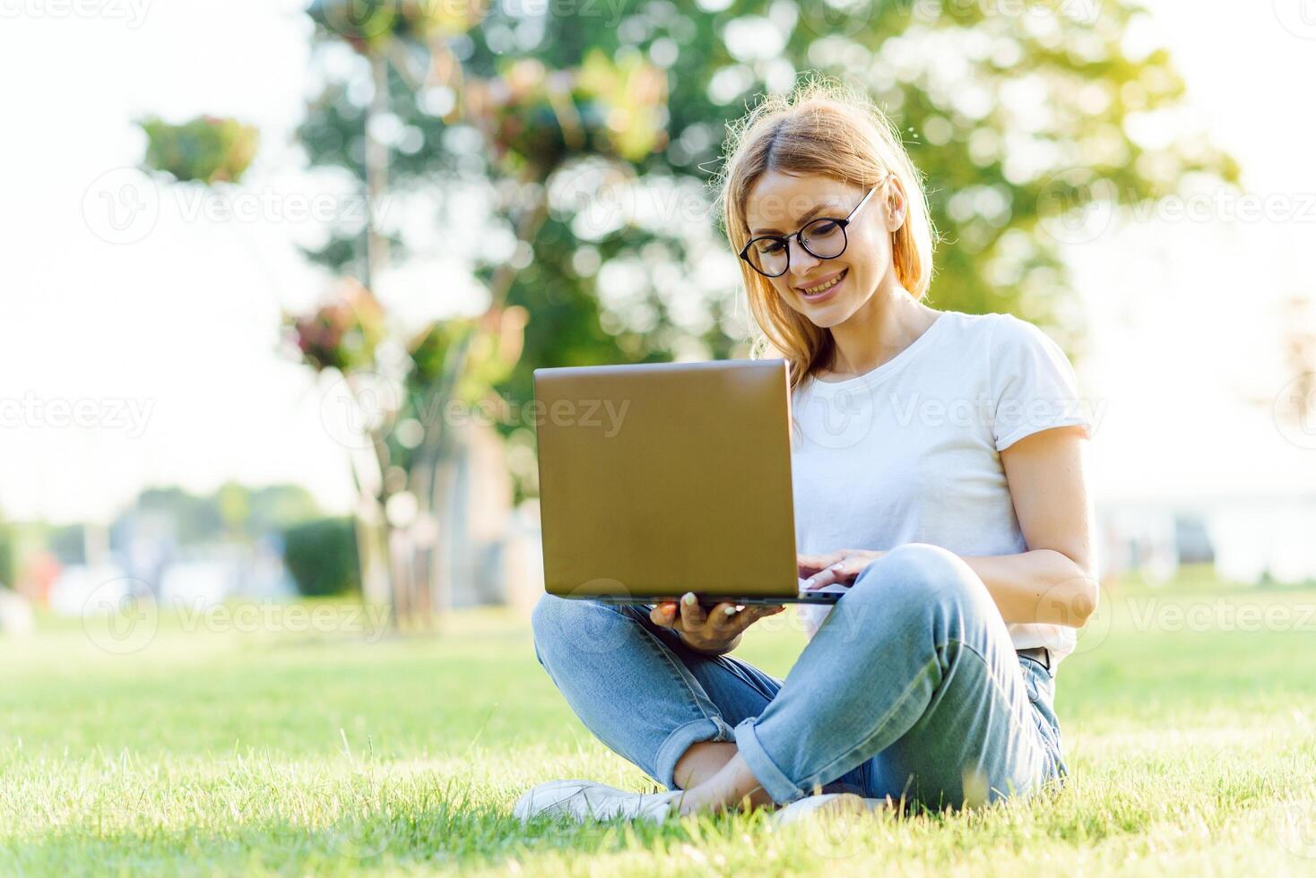 bonita jovem mulher surfar Internet em computador portátil ao ar livre. foto