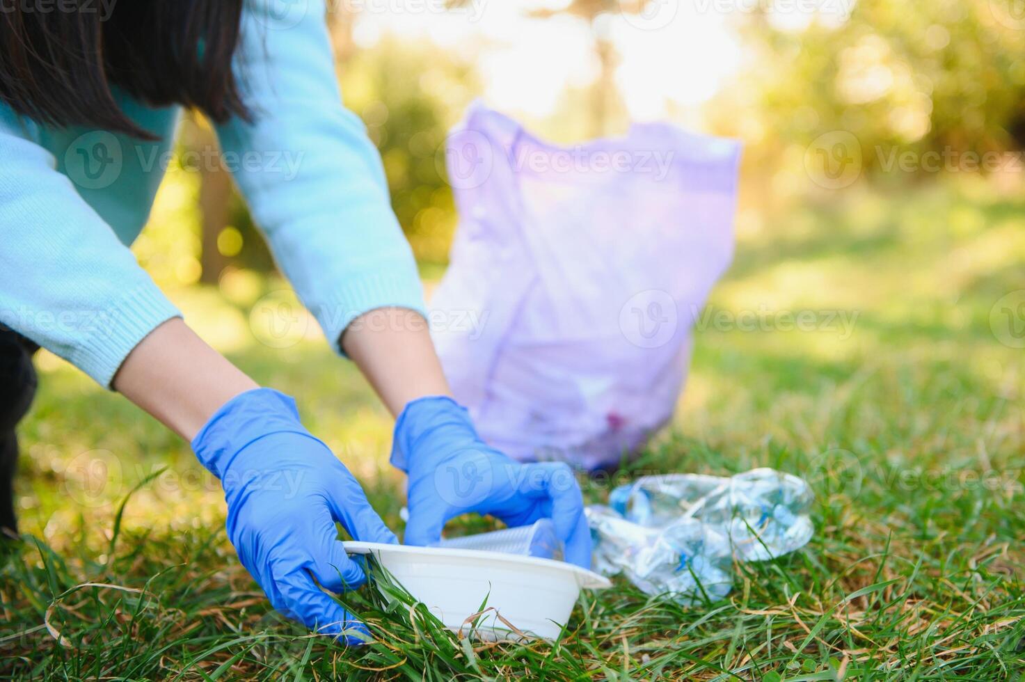 mulheres mãos dentro vermelho borracha luvas. mulher coleta Lixo dentro a bolsa. voluntário limpar lixo dentro a verão parque. agradável progressivo mulher fazer a esforço para Socorro a meio Ambiente foto