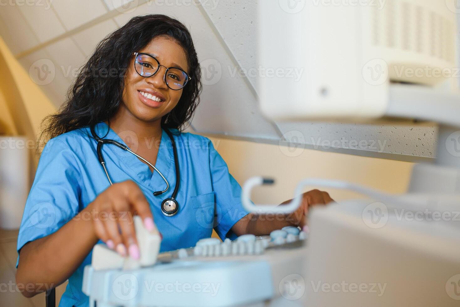 jovem alegre africano mulher operador do a ultrassom digitalização máquina analisando diagnóstico resultados do paciente. jovem sorridente africano médico trabalhando em uma moderno ultrassom equipamento. foto