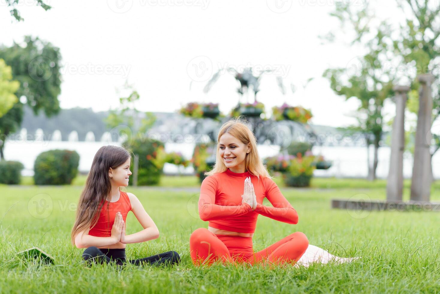 mãe e filha fazendo ioga exercícios em Relva dentro a parque às a dia Tempo foto