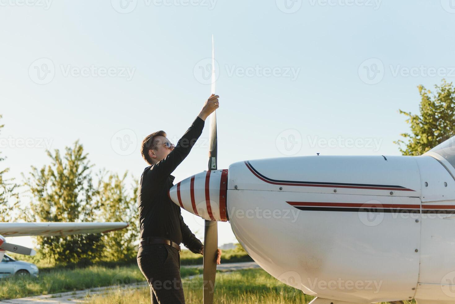 pensativo atraente jovem homem piloto em pé perto pequeno aeronave foto