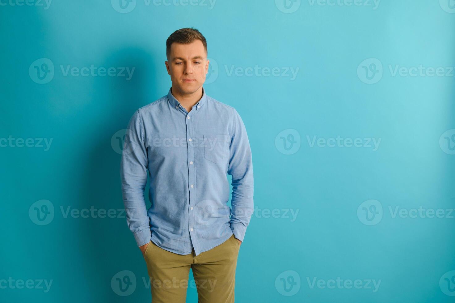 feliz sorridente bonito homem dentro roupas, mostrando cópia de espaço, visual imaginário ou algo, ou pressionando virtual botão, aqua marinho azul cor fundo. foto