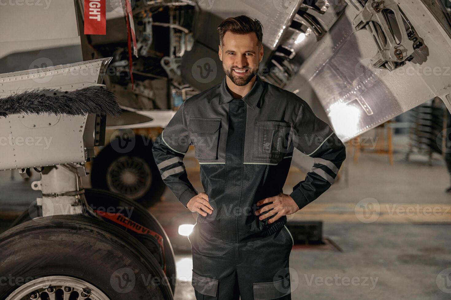 alegre masculino mecânico em pé perto avião dentro hangar foto