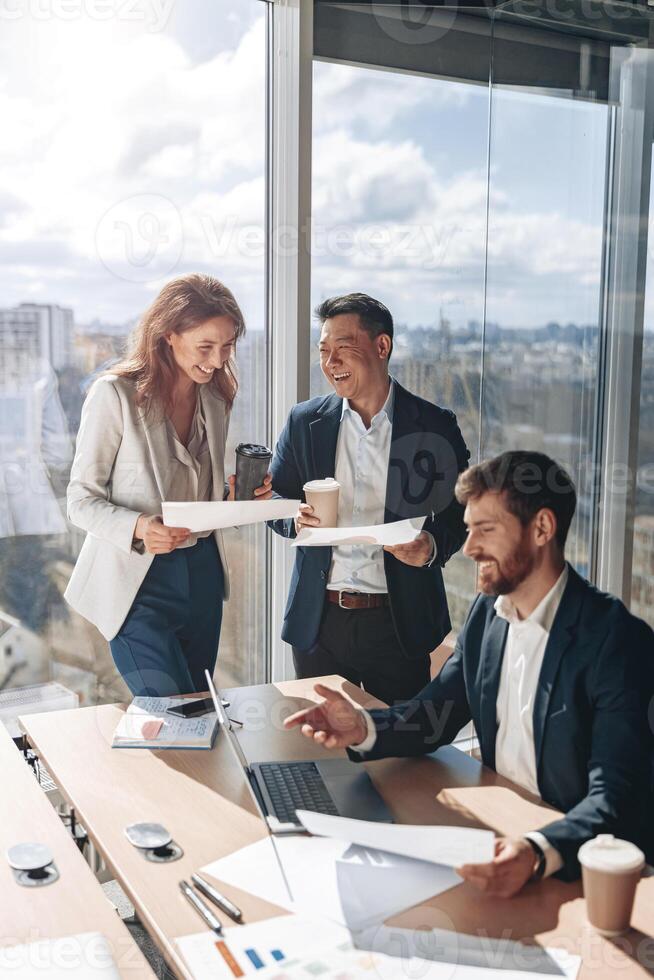 sorridente empresários beber café e discutindo documentos com gráficos e gráficos foto