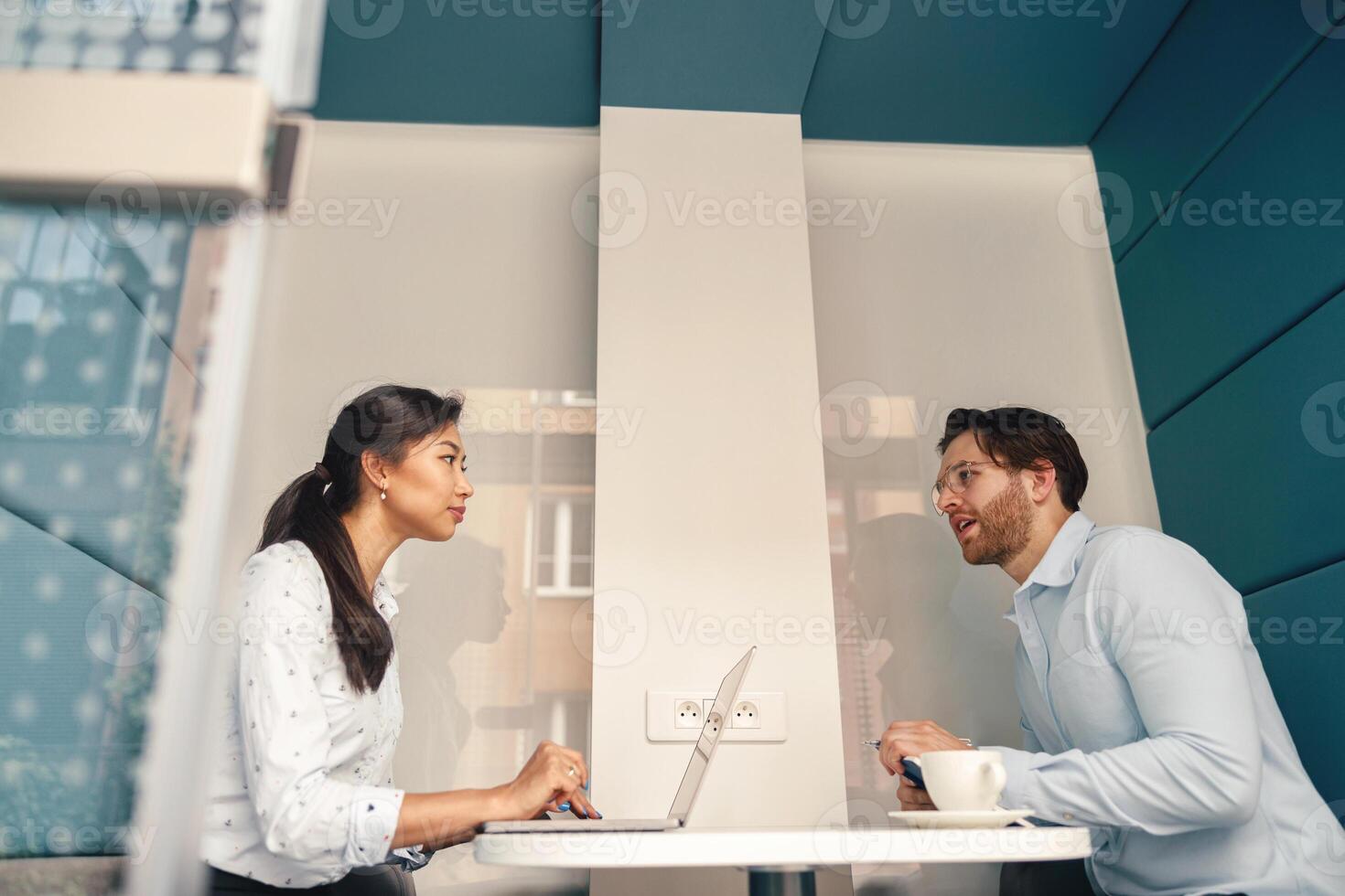 dois diverso o negócio colegas trabalhando juntos em projeto sentado dentro moderno encontro quarto foto