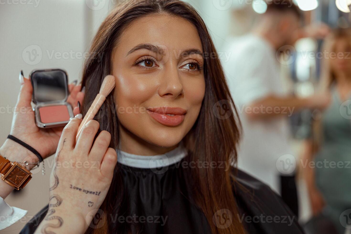 retrato do sorridente mulher obtendo Maquiagem com uma escova dentro beleza salão foto