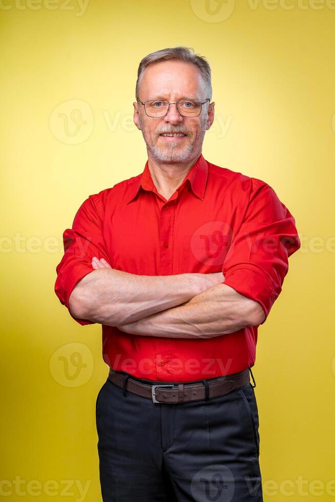 metade comprimento cenário do uma meio envelhecido o negócio homem sorridente com dele braços cruzado. isolado em uma amarelo fundo foto