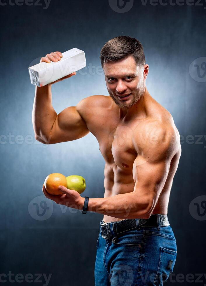 homem atleta com nu tronco dentro uma Preto fundo. fisiculturista detém frutas e suco. estilo de vida conceito. foto