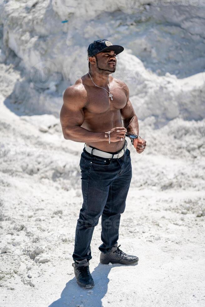 Atlético muscular homem em pé com nu tronco. africano fisiculturista com sem camisa Forte corpo. foto