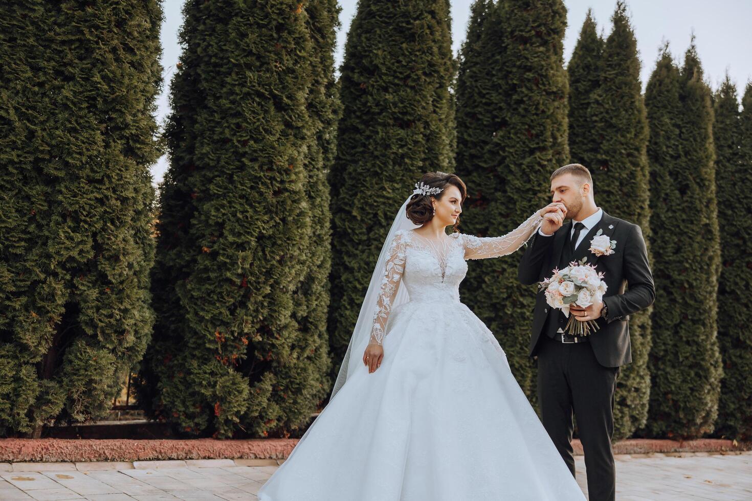 uma Casamento casal é caminhando dentro natureza em a outono dia. feliz jovem noiva e elegante noivo segurando mãos. uma à moda casal do recém-casados em seus Casamento dia. foto