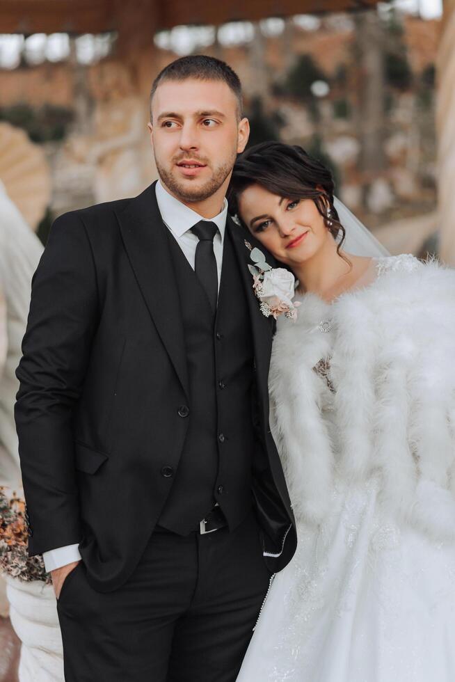 à moda, jovem noivo e lindo noiva dentro uma grandes branco vestir e uma grandes véu com uma ramalhete dentro seus mãos, abraçando dentro a parque dentro a outono natureza. Casamento retrato do recém-casados. foto