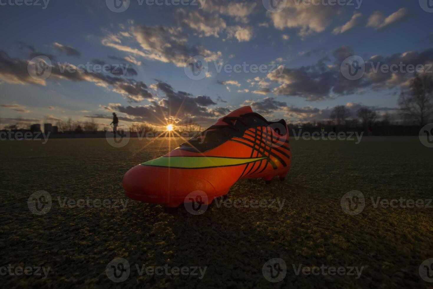 Esportes sapatos em a fundo do a campo às pôr do sol. futebol campo com tênis foto