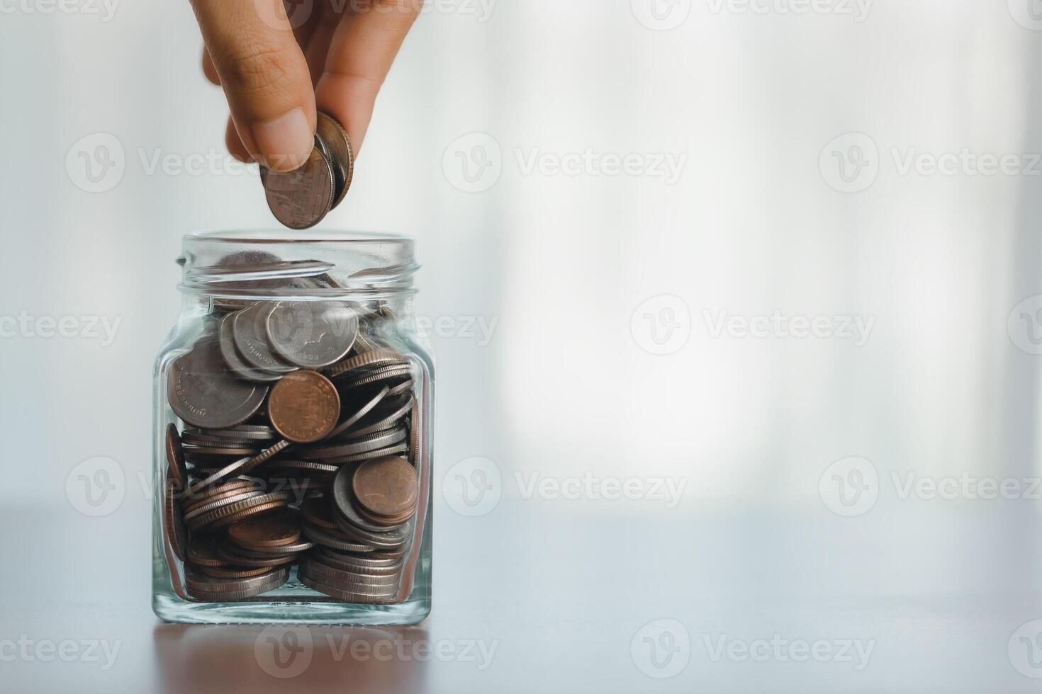 mão colocando moeda dentro vidro jarra para Salve  dinheiro para preparar dentro a futuro. foto