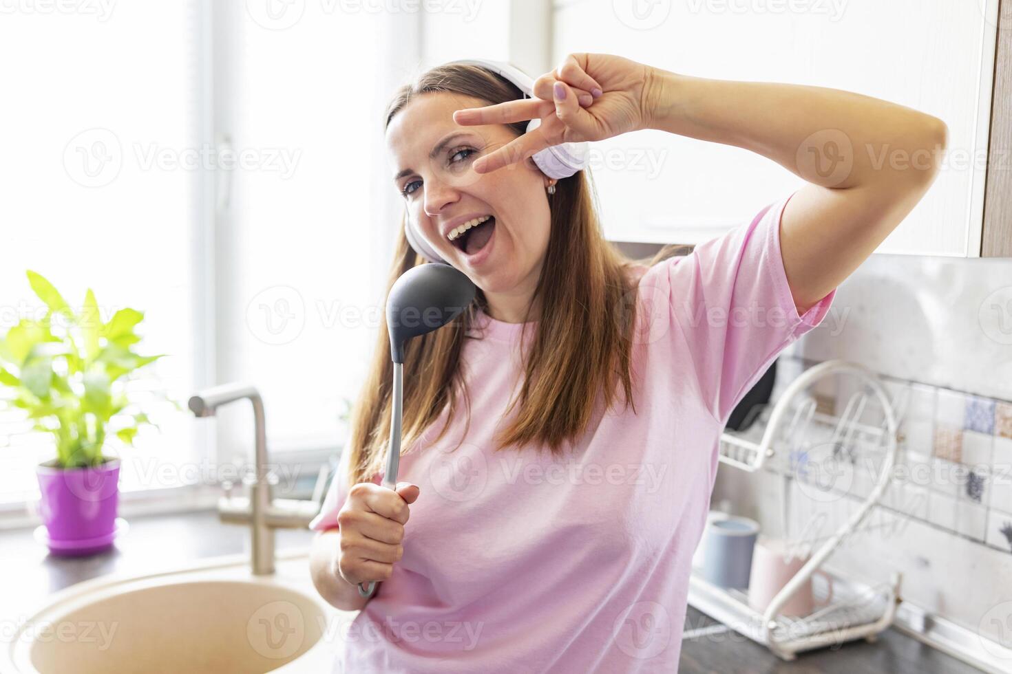 feliz mulher cantando com cozinha concha foto