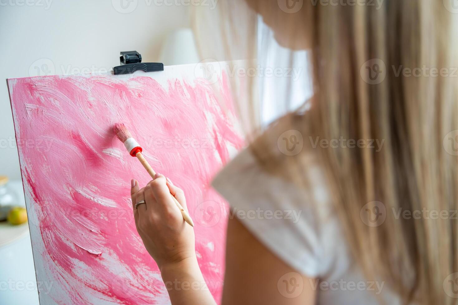 fechar acima Visão do jovem mulher artista com paleta e escova pintura abstrato Rosa cenário em tela de pintura às lar. costas visualizar. arte e criatividade conceito foto