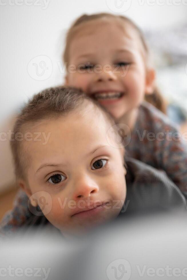 pequeno Garoto com baixa síndrome tocam com dele mais jovem irmã dentro casa quarto. Alto qualidade foto