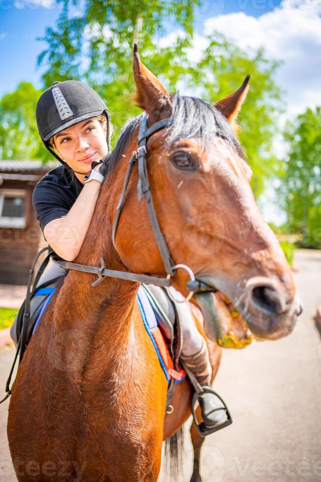 adorável jovem mulher vestindo capacete equitação dela Castanho cavalo foto