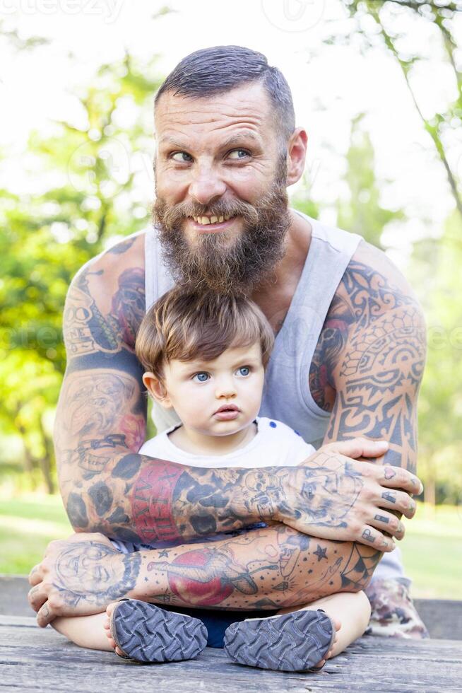 tatuado pai ter Diversão com dele filho dentro a parque foto