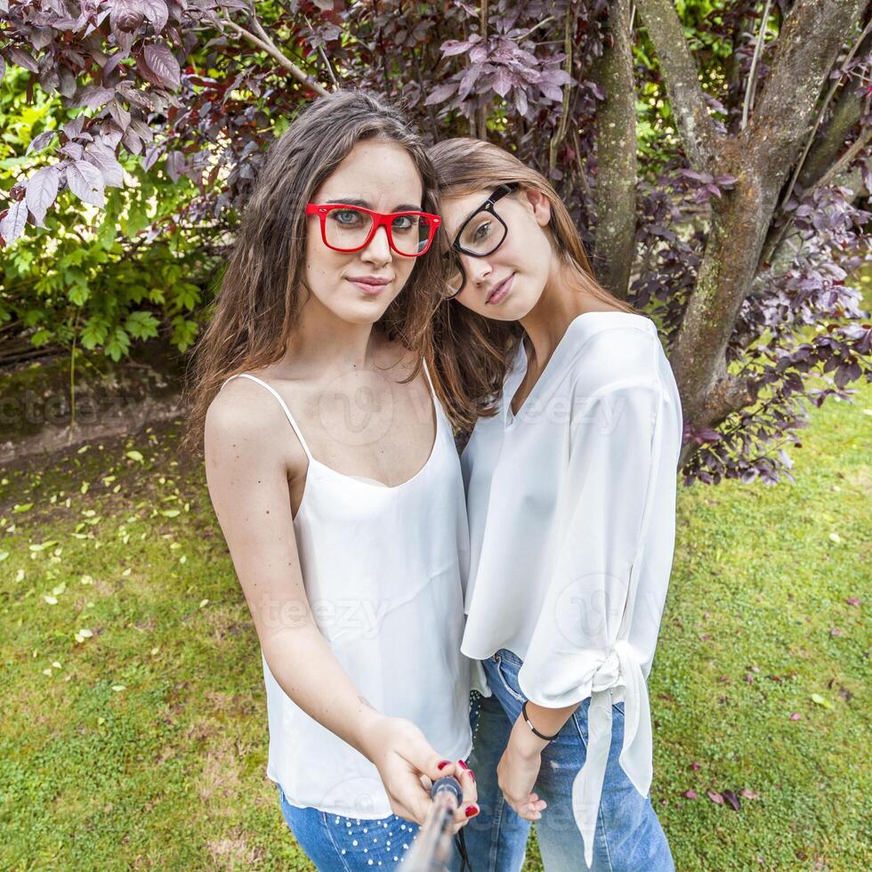 dois fêmea jovem amigos levar uma selfie abraçado juntos foto