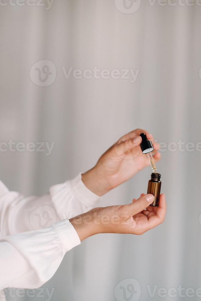 fechar-se do fêmea mãos segurando uma garrafa do essencial óleo, aromaterapia foto