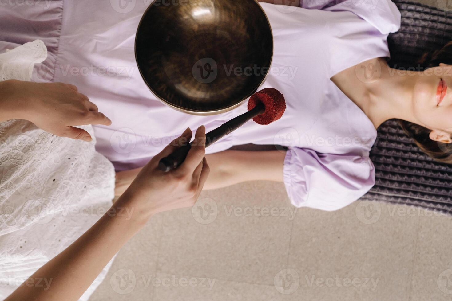 a cobre cantando tigela do a nepalês Buda dentro a spa. uma jovem lindo mulher é fazendo uma massagem com cantando taças dentro uma spa salão contra a pano de fundo do uma cascata foto