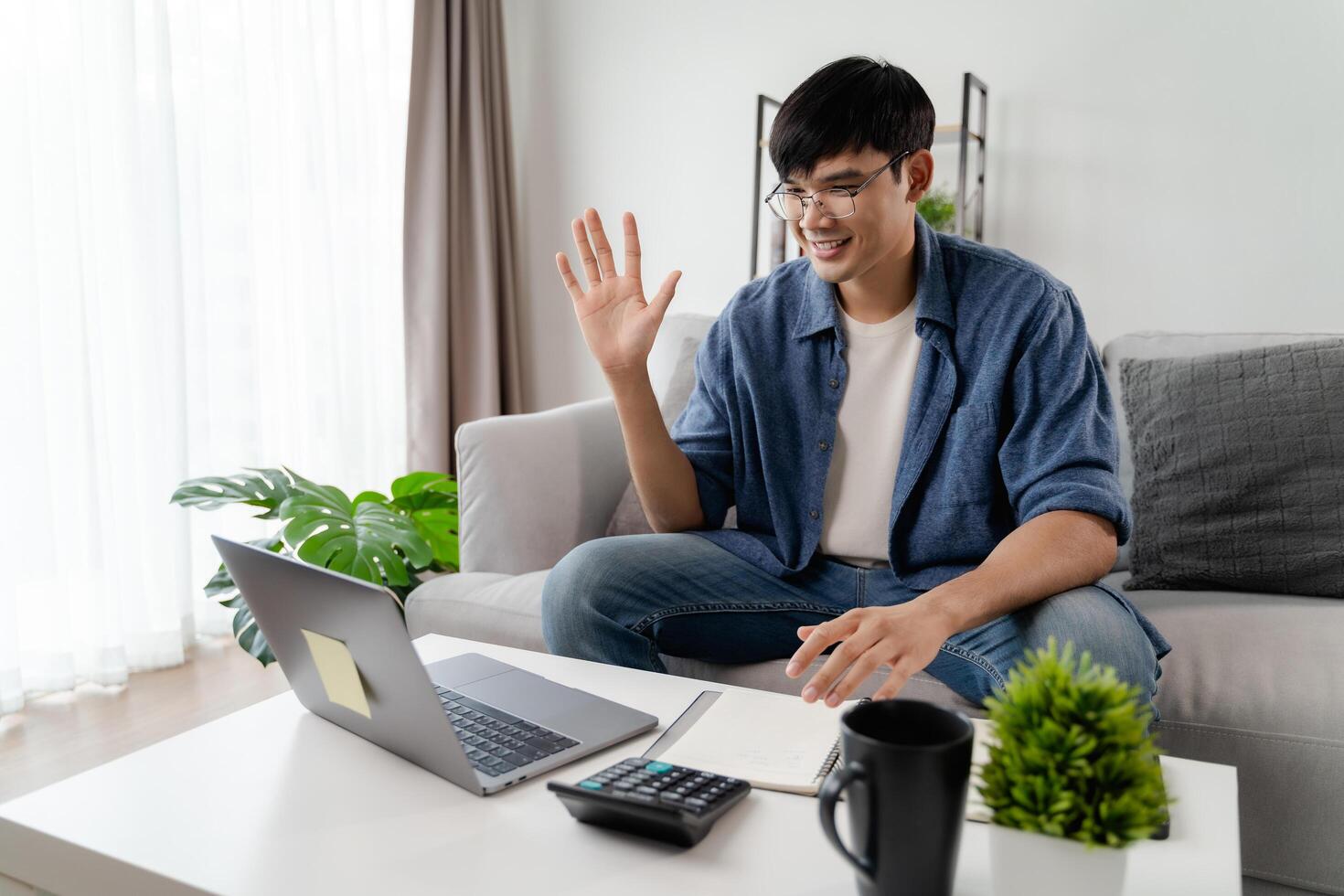 a homem dentro casual roupas trabalhando com uma computador portátil, computador, inteligente telefone, calculadora sentado em a sofá dentro a vivo quarto às lar, trabalhando a partir de casa conceito. foto