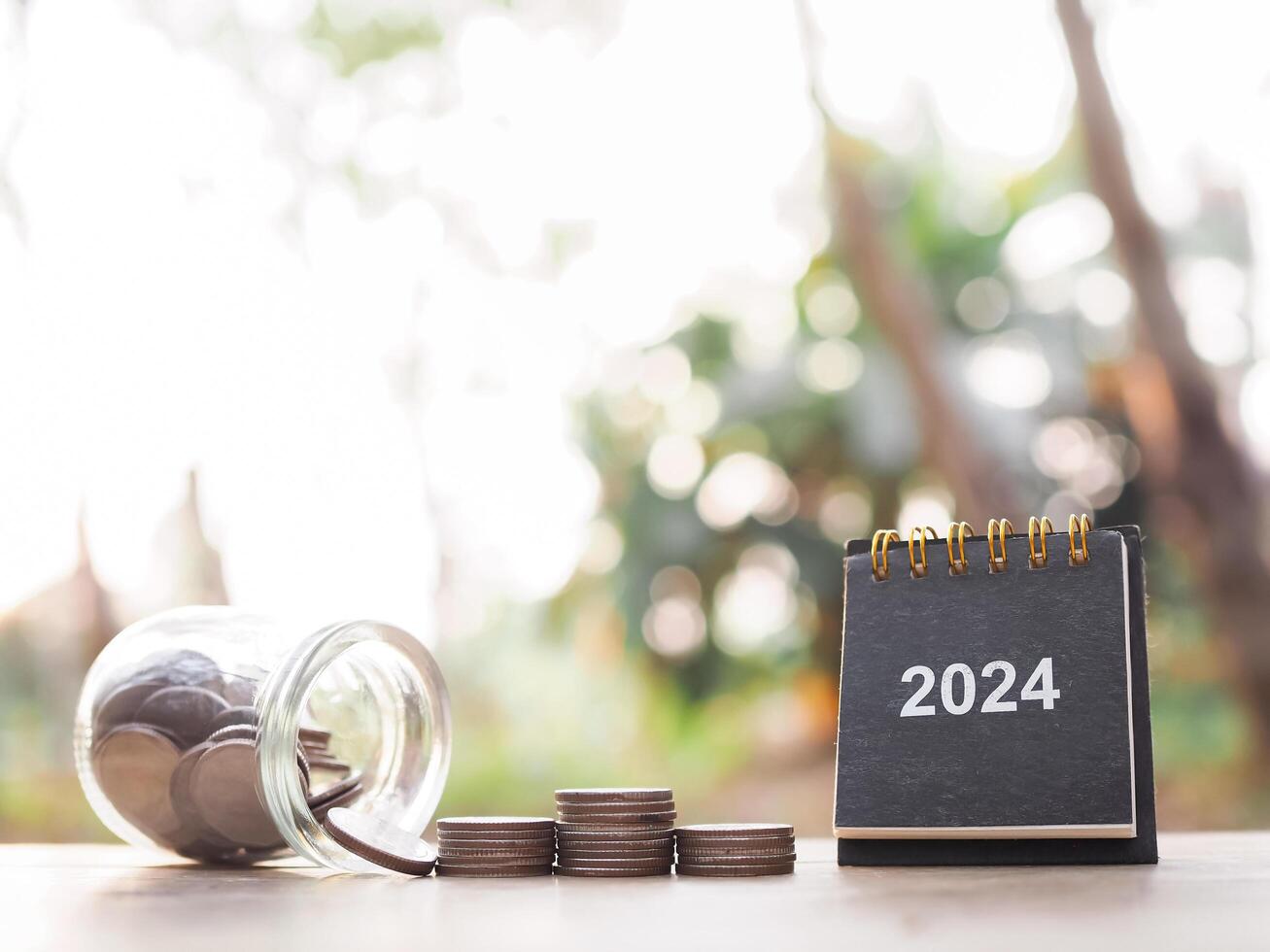 2024 escrivaninha calendário e pilha do moedas. a conceito do salvando dinheiro, financeiro, investimento e o negócio crescendo dentro ano 2024. foto
