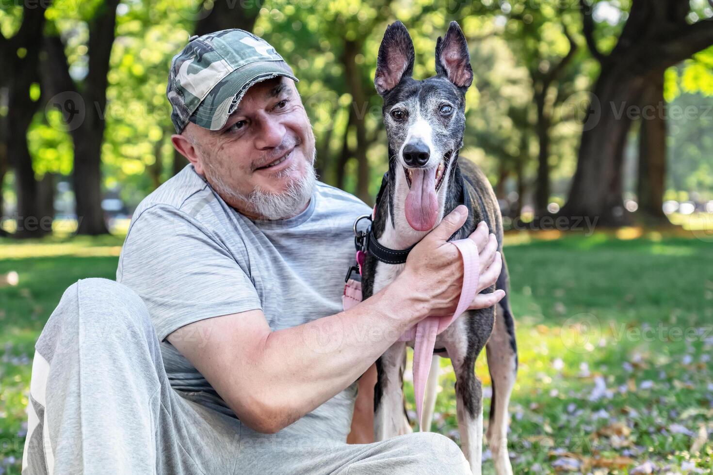 uma maduro Careca homem com dele galgo foto