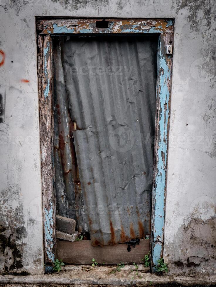 uma estragado porta coberto com zinco Pranchas dentro uma casa este tem fui abandonado de Está proprietário foto