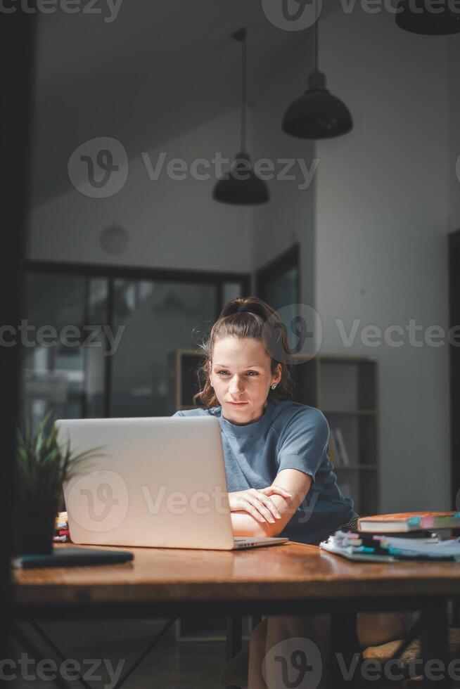 uma mulher, profundamente absorta dentro dela trabalhar, inclina-se frente para dela computador portátil tela, dela expressão 1 do intenso foco e determinação dentro uma bem iluminado moderno escritório. foto