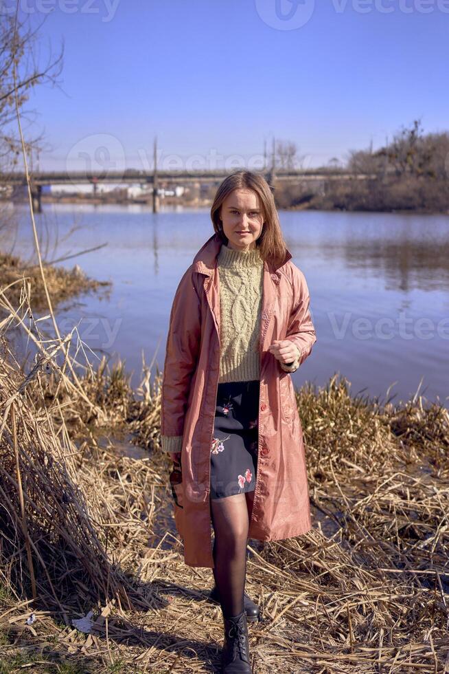 retrato do uma lindo jovem mulher em a rio banco foto