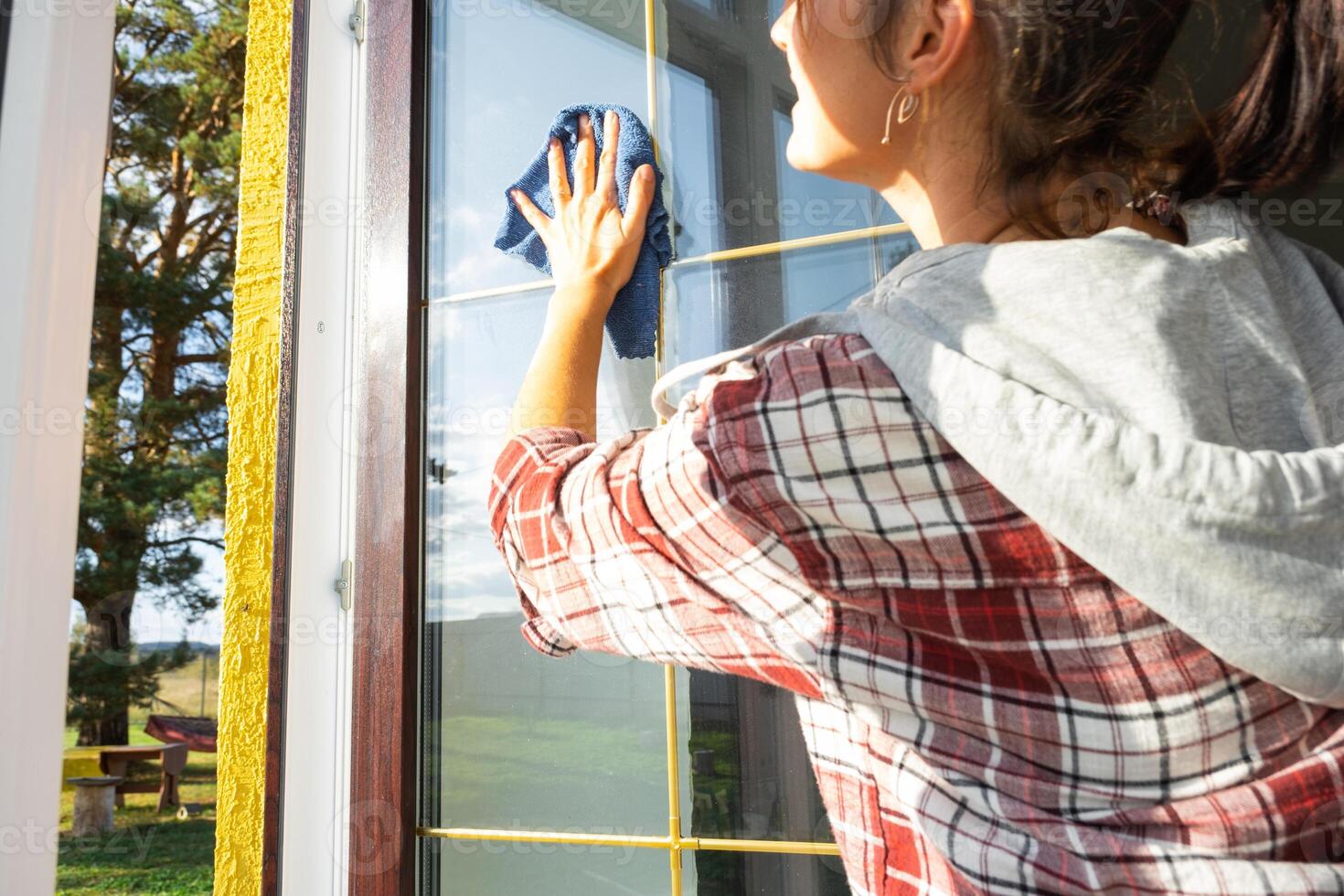 mulher manualmente lavagens a janela do a casa com uma trapo com spray limpador e esfregão dentro a interior com branco cortinas. restaurando ordem e limpeza dentro a primavera, limpeza servise foto