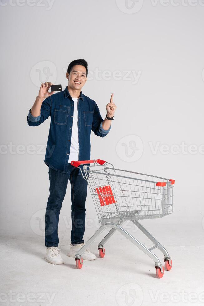 feliz sorridente homem empurrando supermercado carrinho isolado em branco fundo foto