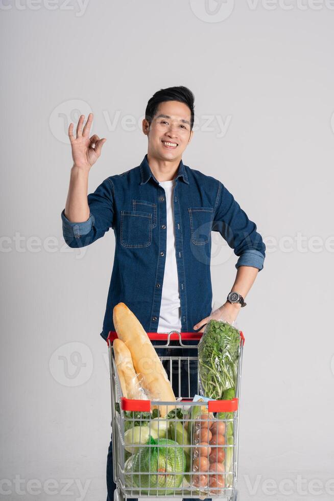 feliz sorridente homem empurrando supermercado carrinho isolado em branco fundo foto