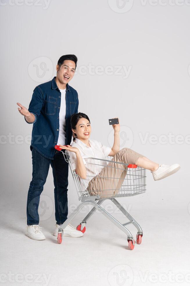 feliz sorridente casal empurrando supermercado carrinho isolado em branco fundo foto