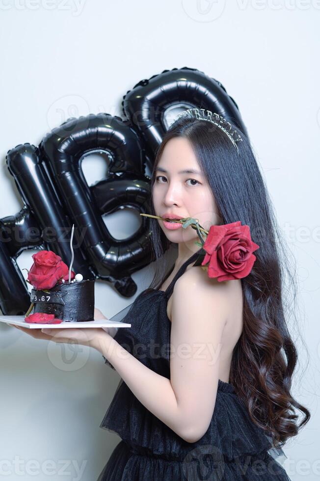 lindo mulher vestindo uma Preto vestir e chocolate bolo dentro a conceito do aniversário foto