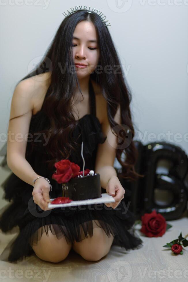 lindo mulher vestindo uma Preto vestir e chocolate bolo dentro a conceito do aniversário foto
