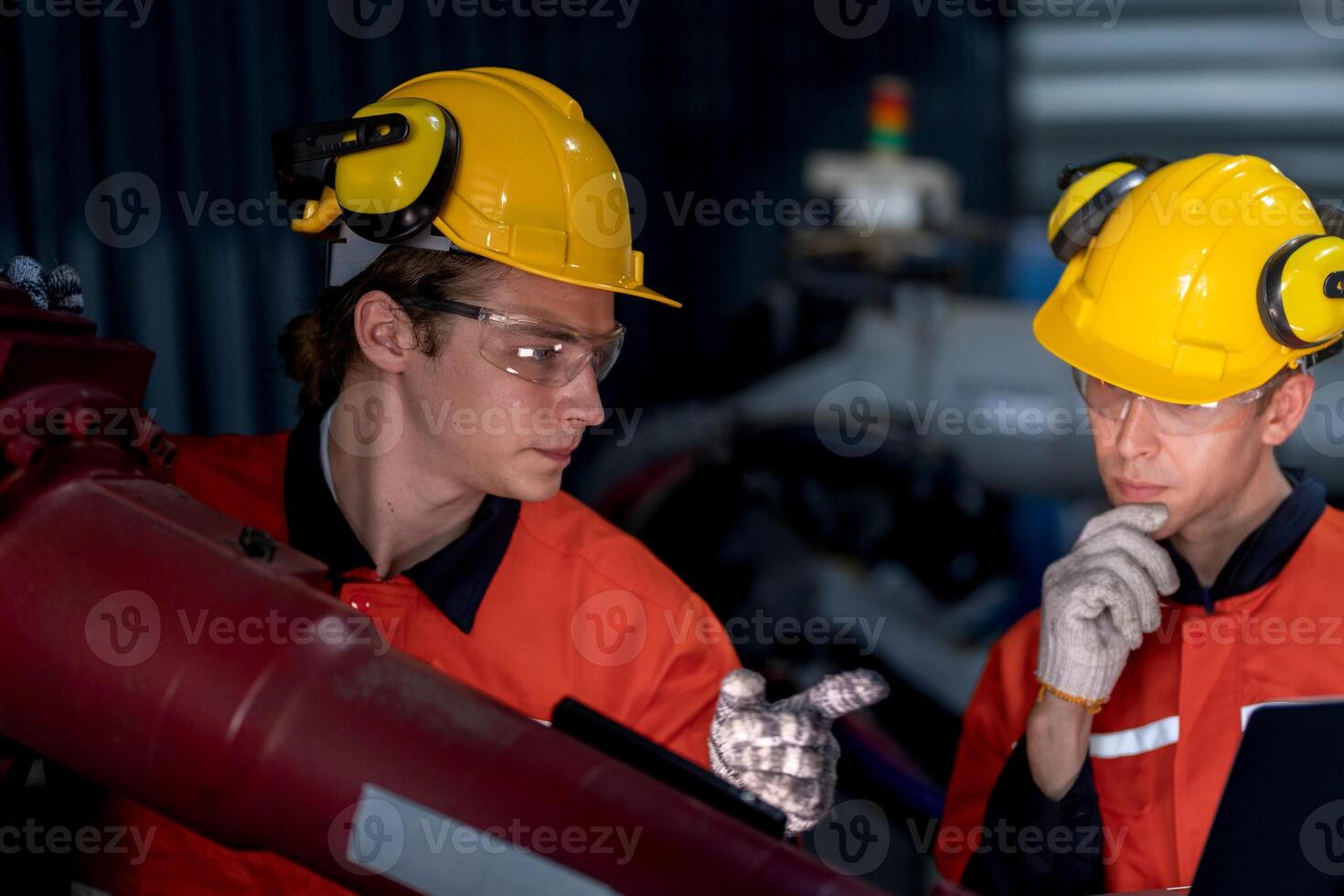 grupo do masculino engenheiro trabalhadores manutenção automático robótico braço máquina dentro uma Sombrio quarto fábrica. trabalhador verificação e reparação automático robô mão máquina. trabalhador vestindo segurança óculos e capacete. foto