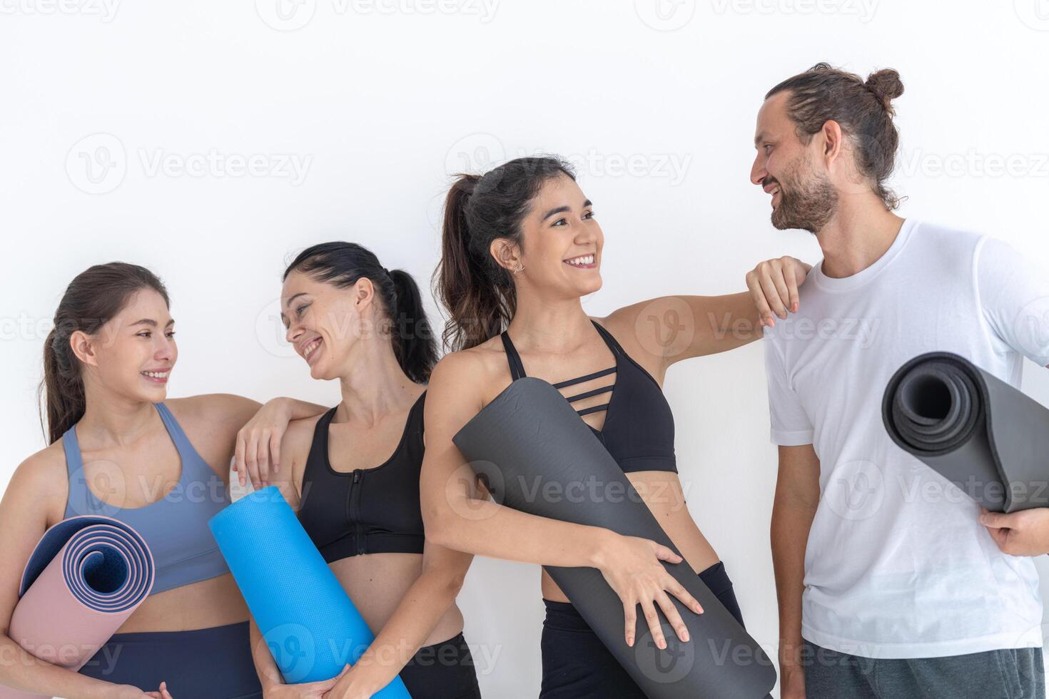 grupo do feliz desportivo mulheres e cara vestindo corpo à moda roupa de esporte segurando pessoal tapetes inclinou-se em uma branco fundo. esperando para ioga classe ou corpo peso aula. saudável estilo de vida e bem estar foto