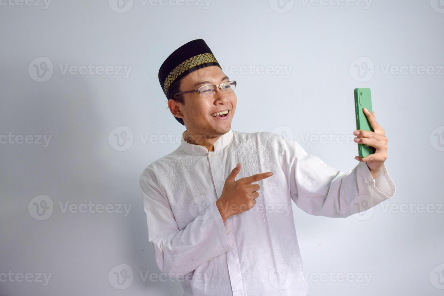 ásia muçulmano homem vestindo óculos e branco pano apontando telefone pose para Ramadhan e eid al fitr. isolado branco fundo foto