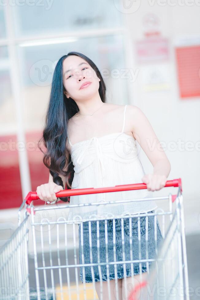 ásia mulher empurrando compras carrinho dentro compras Shopping foto