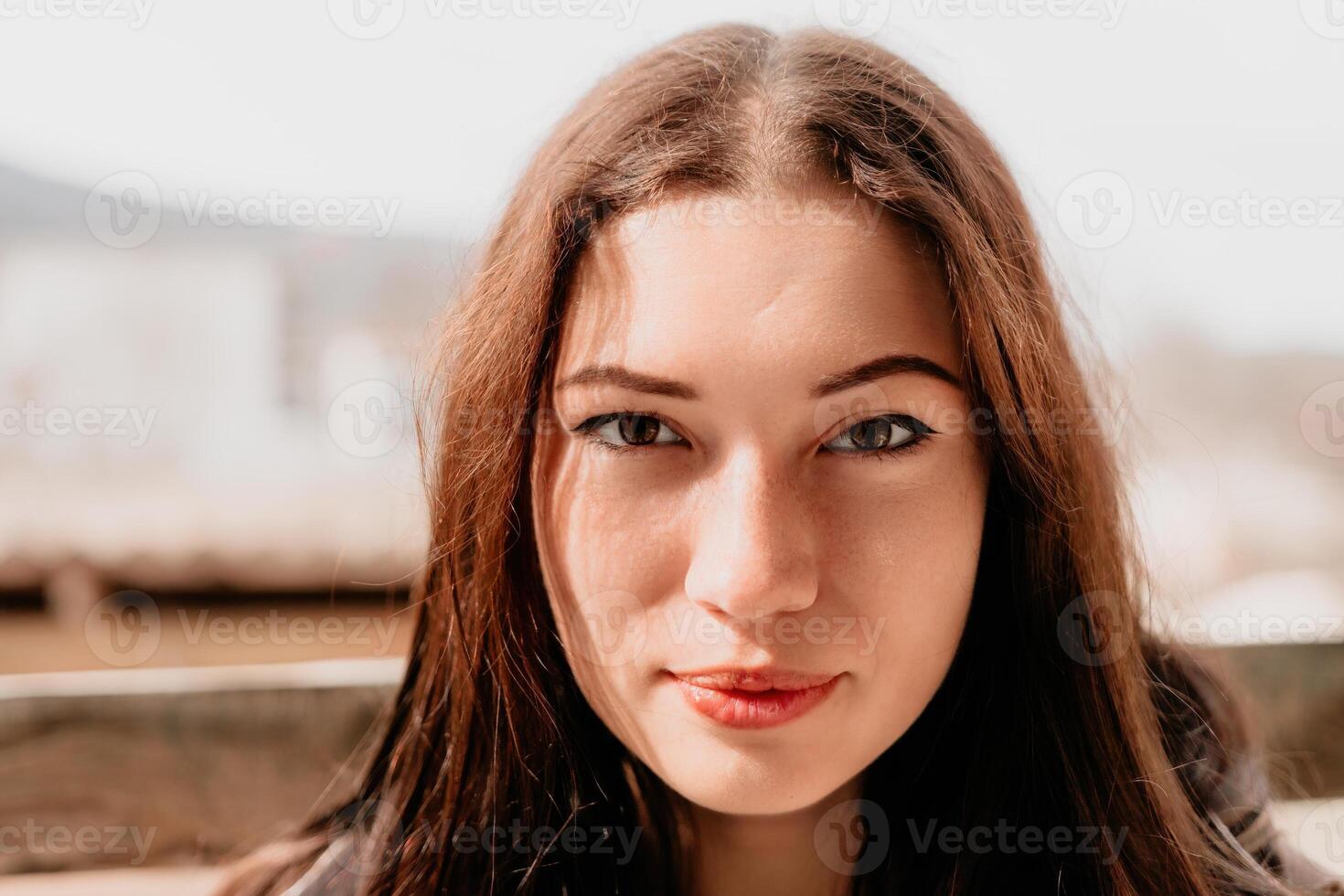 feliz jovem sorridente mulher com sardas ao ar livre retrato. suave ensolarado cores. ao ar livre fechar-se retrato do uma jovem morena mulher e olhando para a Câmera, posando contra outono natureza fundo foto