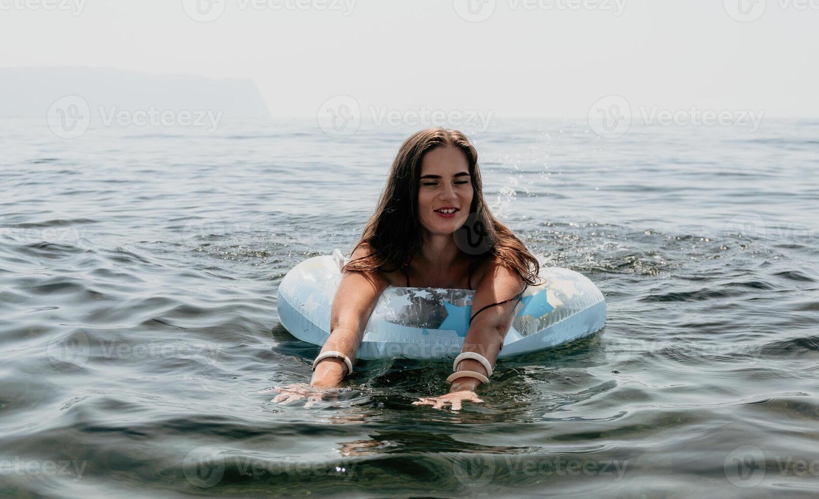 mulher verão mar. feliz mulher natação com inflável rosquinha em a de praia dentro verão ensolarado dia, cercado de vulcânico montanhas. verão período de férias conceito. foto