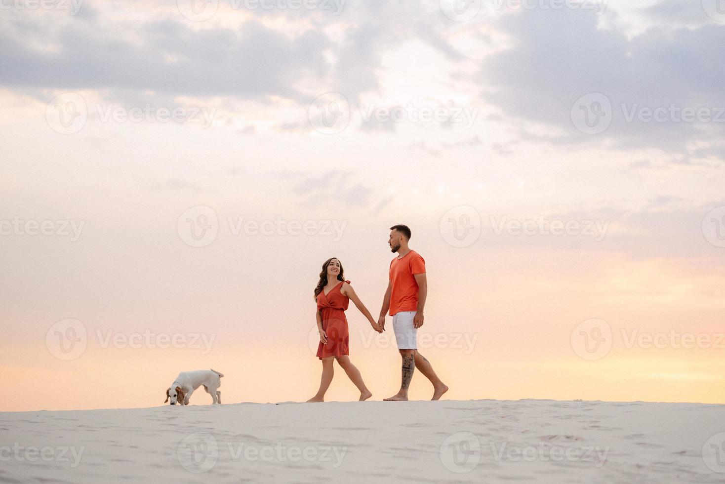 jovem casal em roupas laranja com cachorro foto