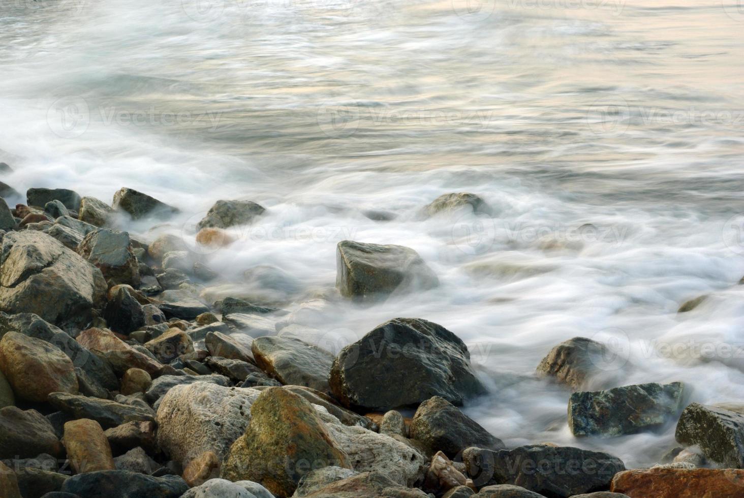 turbulência água do mar e rocha na costa foto