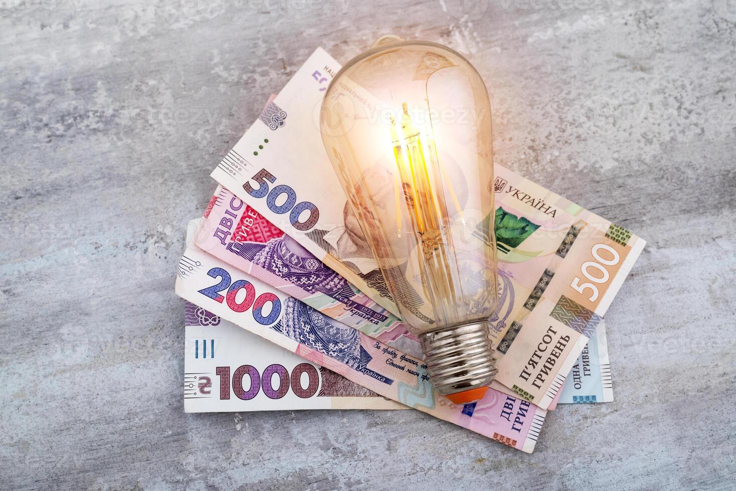 ucraniano dinheiro hryvnias e uma luz lâmpada. a conceito do aumentando eletricidade preços dentro Ucrânia e a déficit. eletricidade custos foto