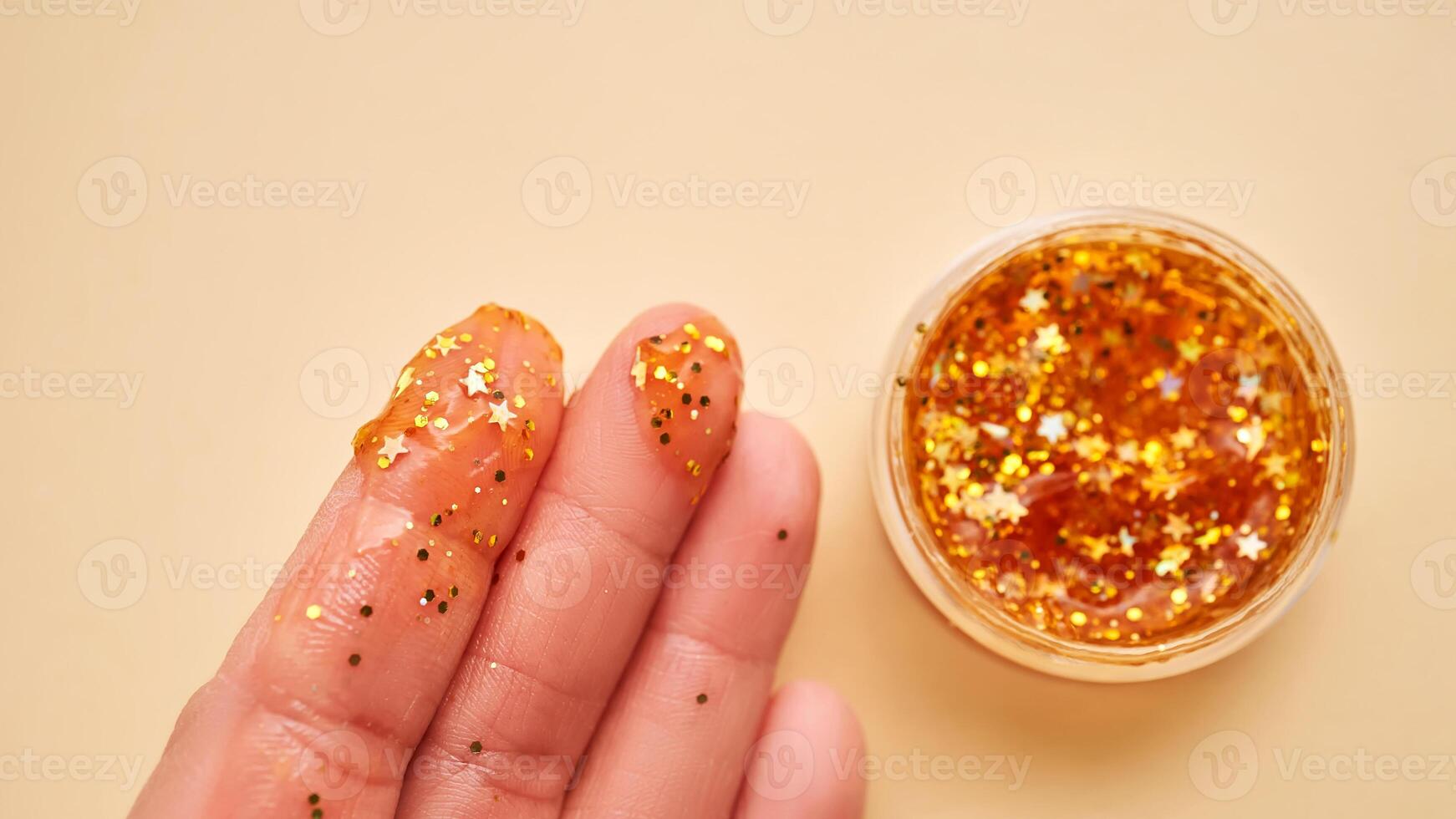 Cosmético gel com brilhar em mulheres dedos em uma bege fundo. foto